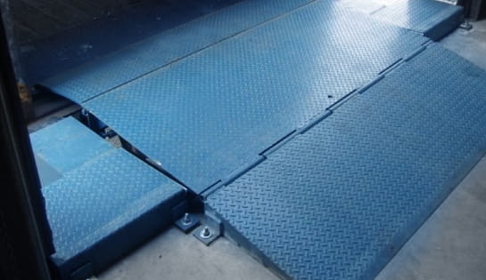 Blue surface-mounted dock leveler installed at a warehouse loading bay