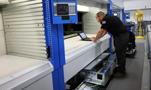 Raymond Storage Concepts technician connecting a laptop to an automated storage and retrieval system mechanical drawer to review software configurations