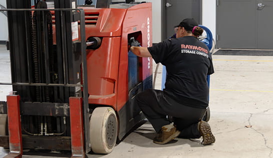 Raymond Storage Concepts female technician using a watering gun to service a lead-acid battery in a Raymond counterbalanced truck
