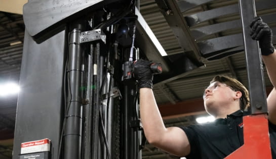 Raymond Storage Concepts shop technician using an electric drill to secure overhead protection on a forklift