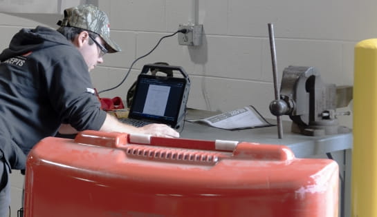 Raymond Storage Concepts technician reviewing laptop diagnostic notes next to a forklift during a service visit