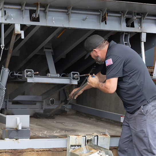 RSC technician sweeping out debris from underneath a dock leveler.