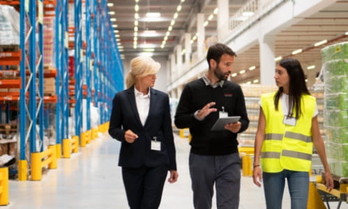 Raymond Storage Concepts account manager walking and talking with a female operations manager and warehouse worker in a facility