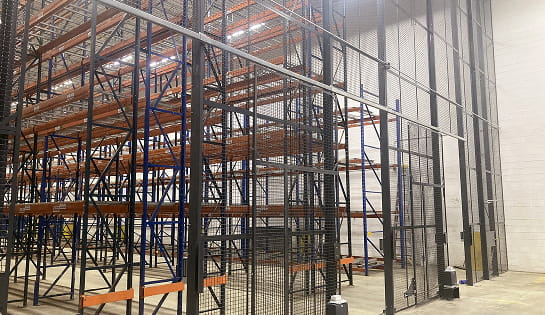 Wire security cage surrounding warehouse storage racking for secure inventory protection
